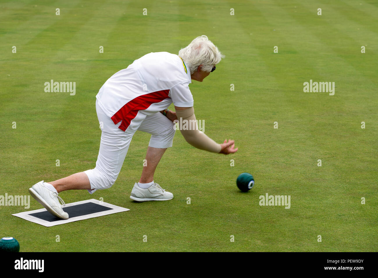 A player bowling a wood at the national women`s lawn bowls
